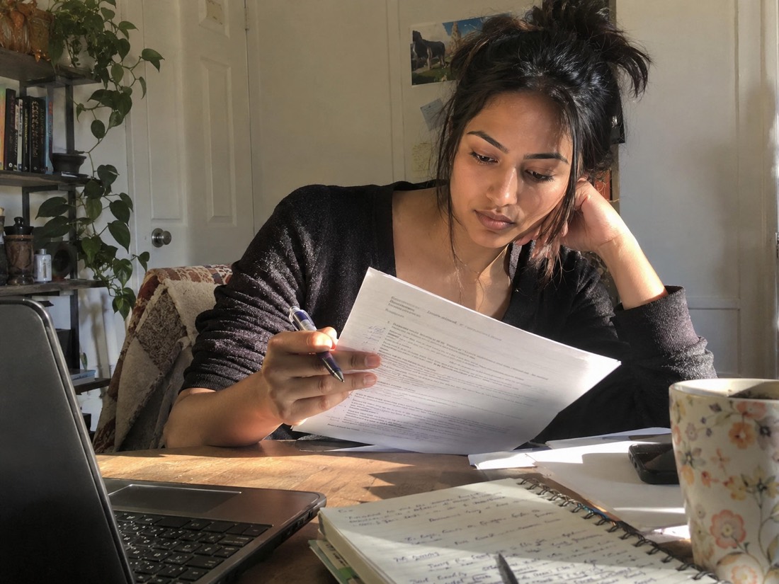 Person reviewing job search materials while using a laptop